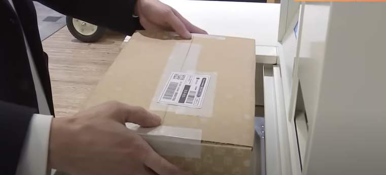 A man uses a smart machine to send a Mercari package.